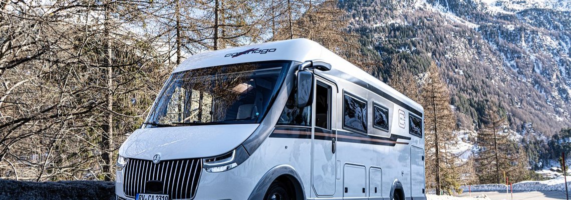 Bild eines Carthago chic c-line I Wohnmobils auf einer Straße inmitten eines Bergpanoramas