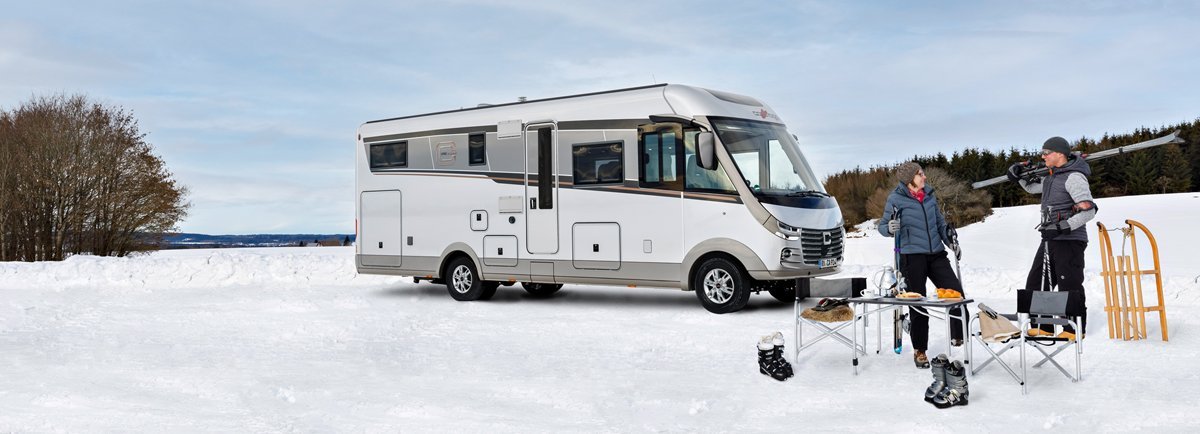Carthago Wohnmobil s-plus in einer Schneelandschaft mit zwei Menschen
