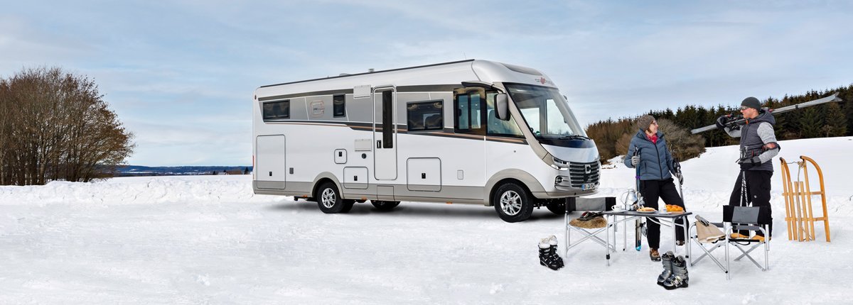 Carthago Wohnmobil s-plus in einer Schneelandschaft mit zwei Menschen