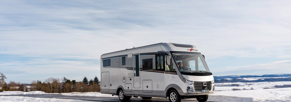 Schneelandschaft Carthago Wohnmobil s-plus fahrend auf der Straße
