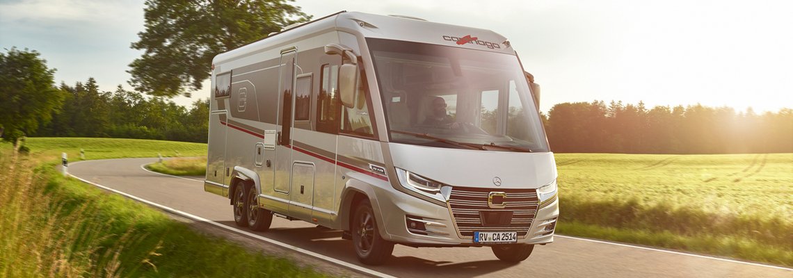 Fahraufnahme Carthago Wohnmobil e-line auf Straße mit Baum im Hintergrund